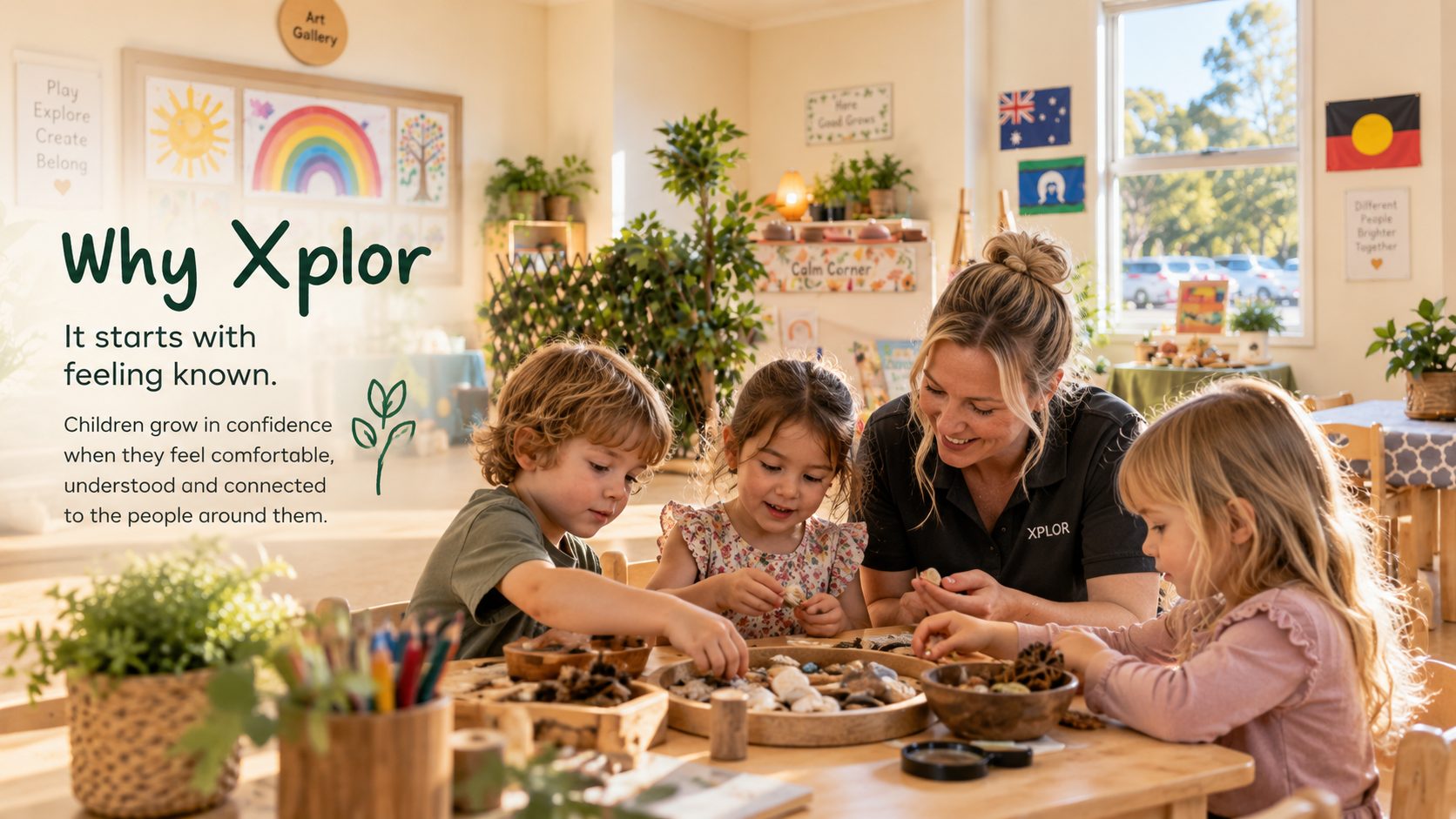 An educator sitting at a wooden table with three children exploring loose parts in a bright Xplor Coomera kindergarten room