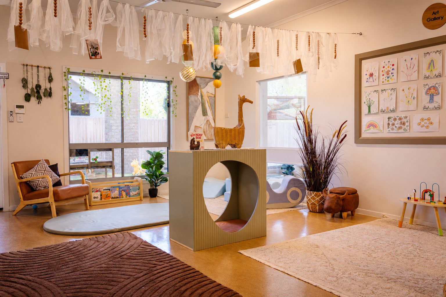 Babies indoor learning space at Xplor Coomera with a green climbing arch, floor mats and framed artwork
