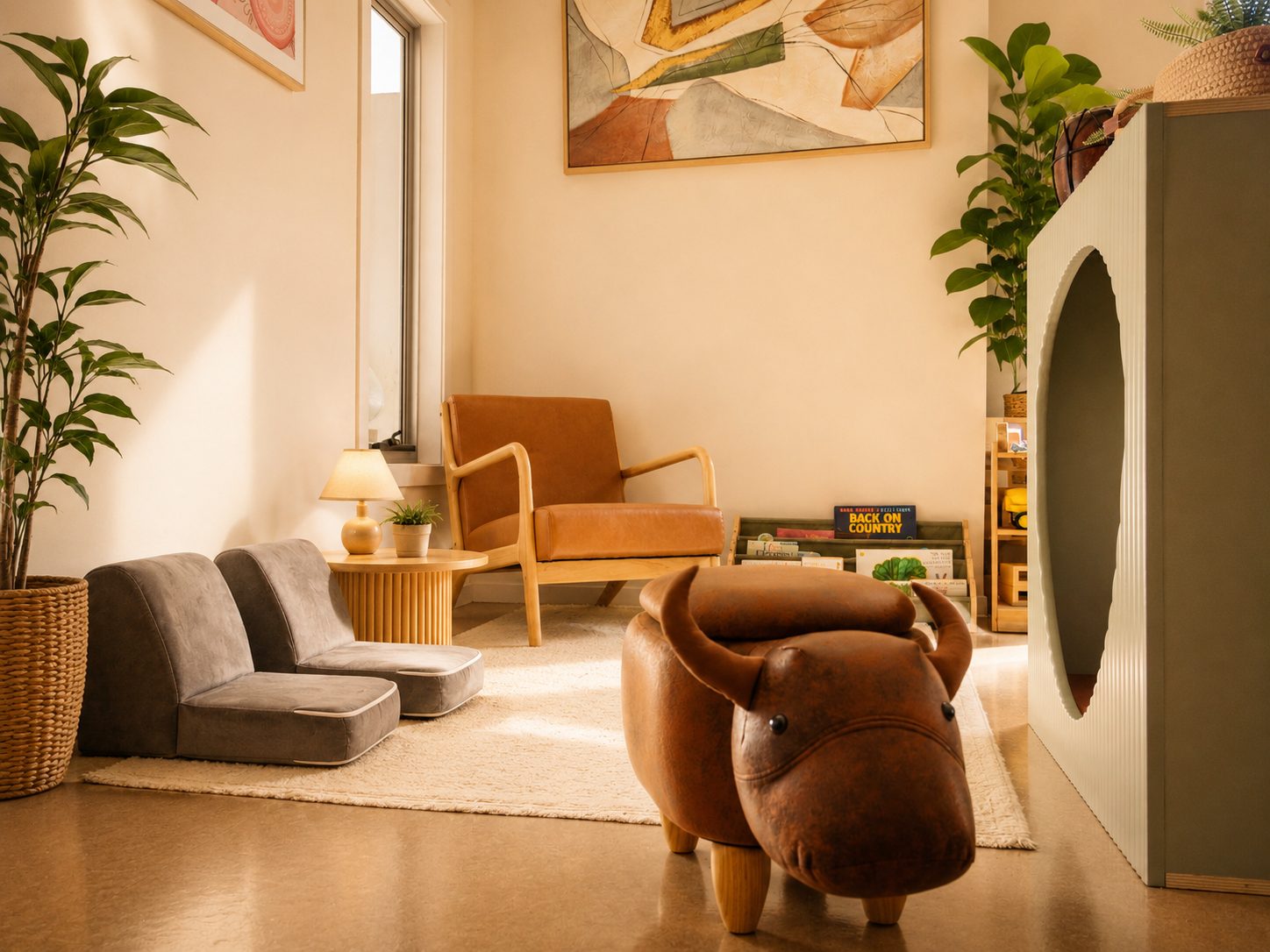 Toddler 1 reading area at Xplor Coomera with an armchair, soft seating and a book display beside a tall plant